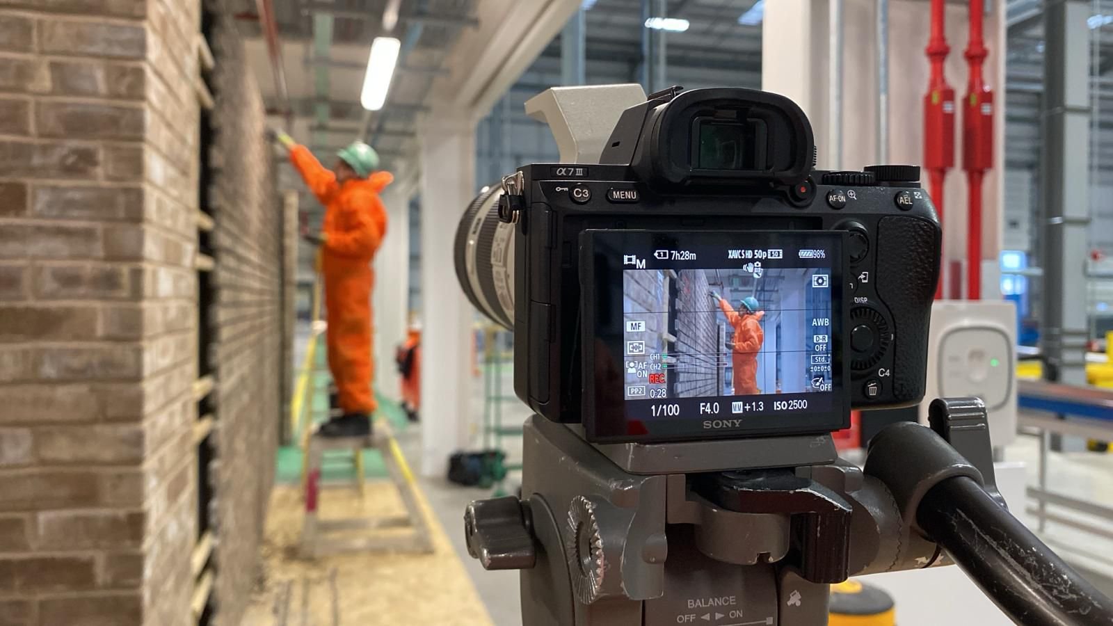 The camera preview of a tradesman working, you can see him in the background too wearing an orange jumpsuit